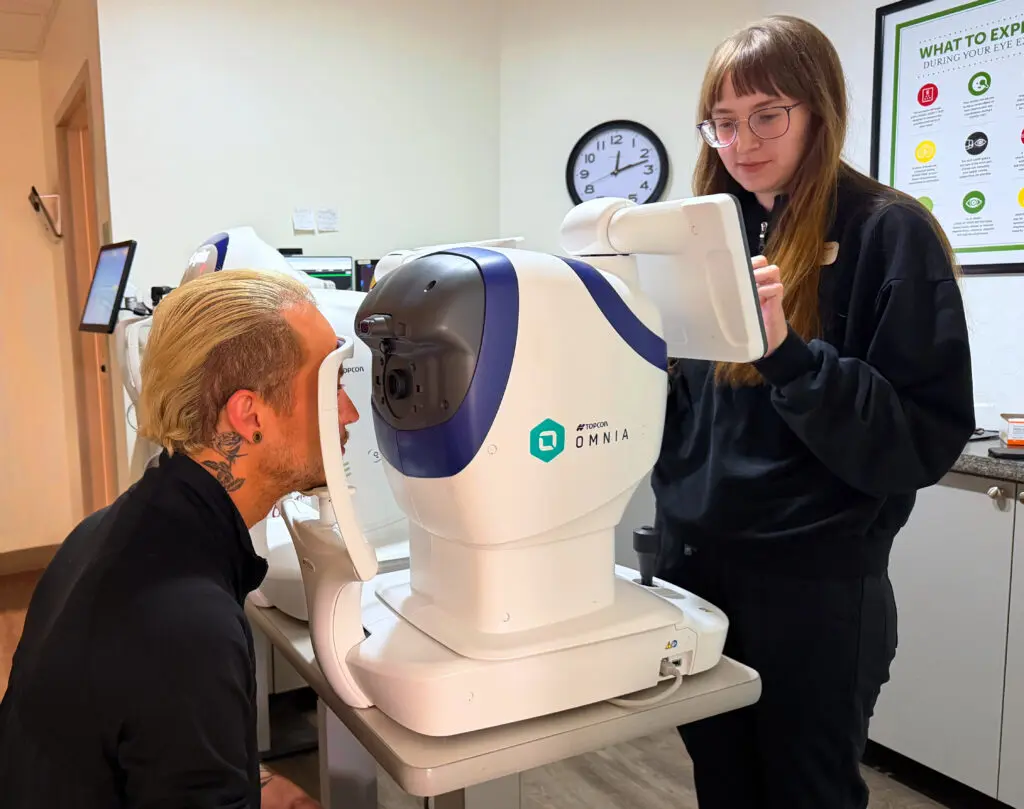 Optometric technician operating a Topcon advanced retinal imaging system during an eye exam at Maple Grove Eye Doctors