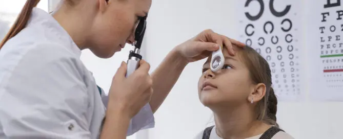 Optometrist examining a young girl's eyes during her first eye exam