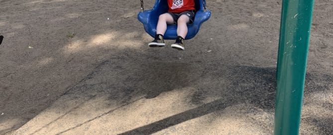 kid on swing wearing sunglasses . Maple Grove Eye Dcotors