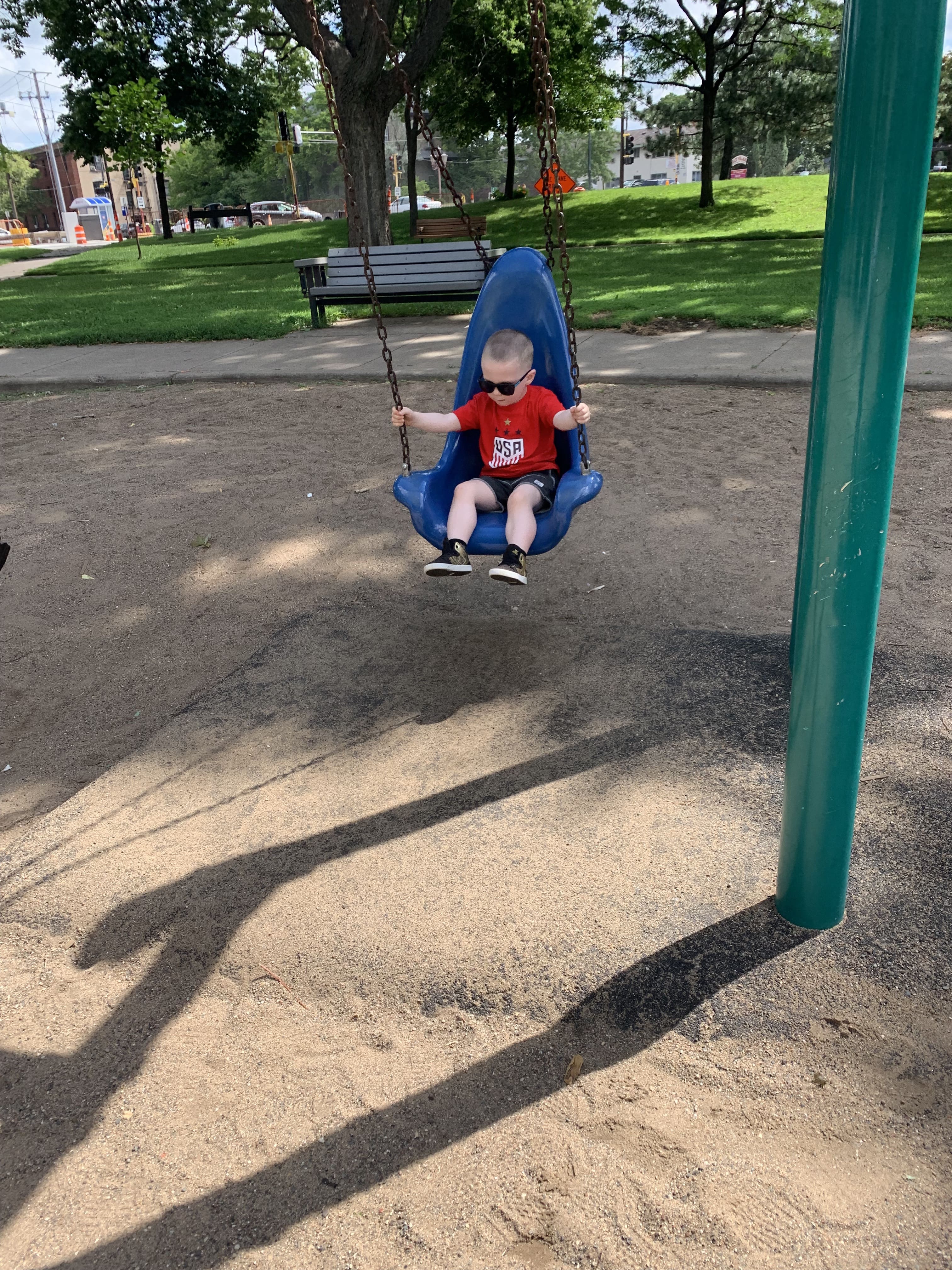 kid on swing wearing sunglasses . Maple Grove Eye Dcotors