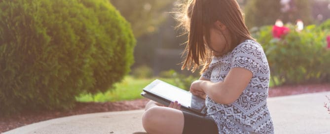Girl Using Ipad Outdoors Maple Grove Eye Doctors at Pearle Vision